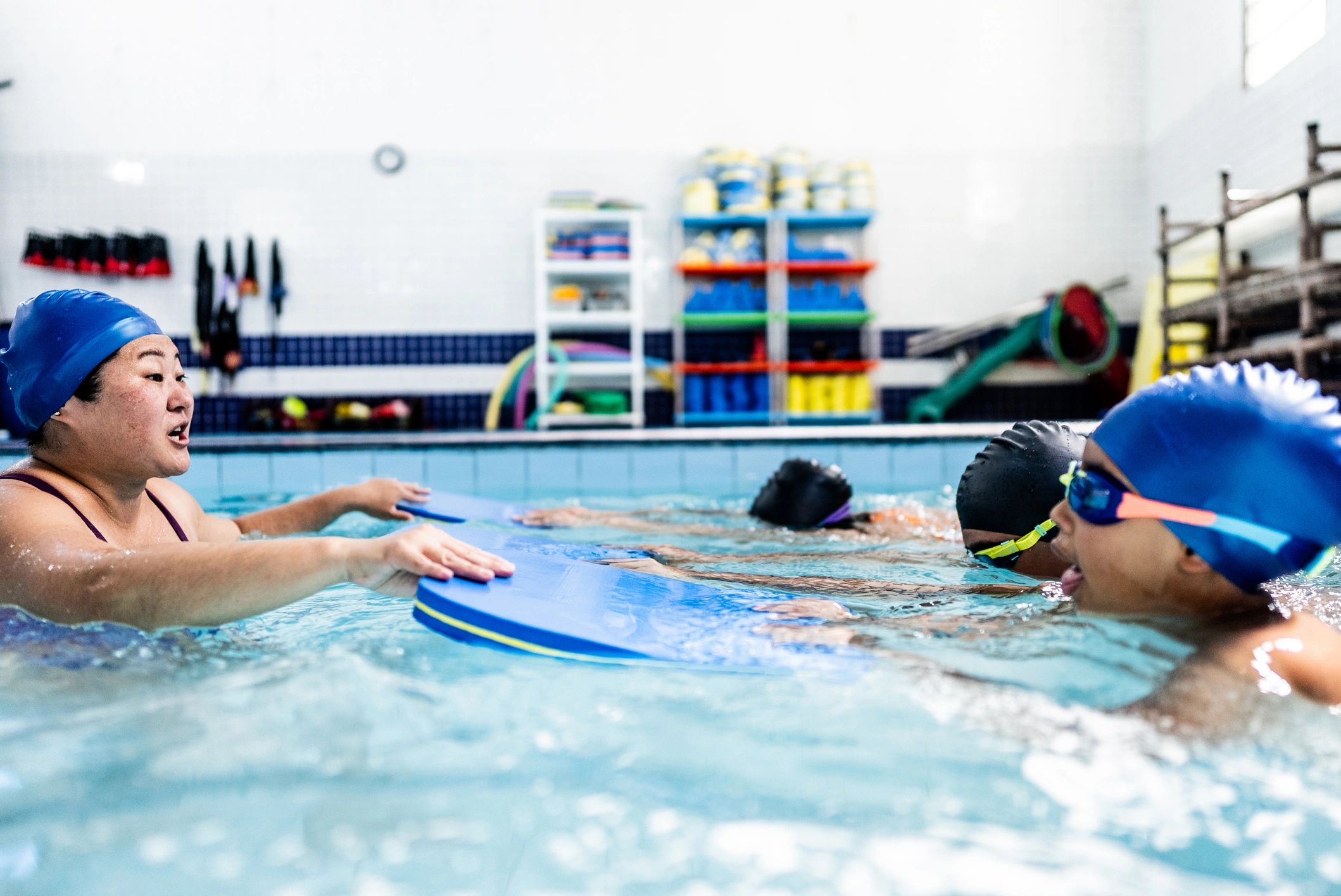 Instructor conversando con niños durante clase de natación